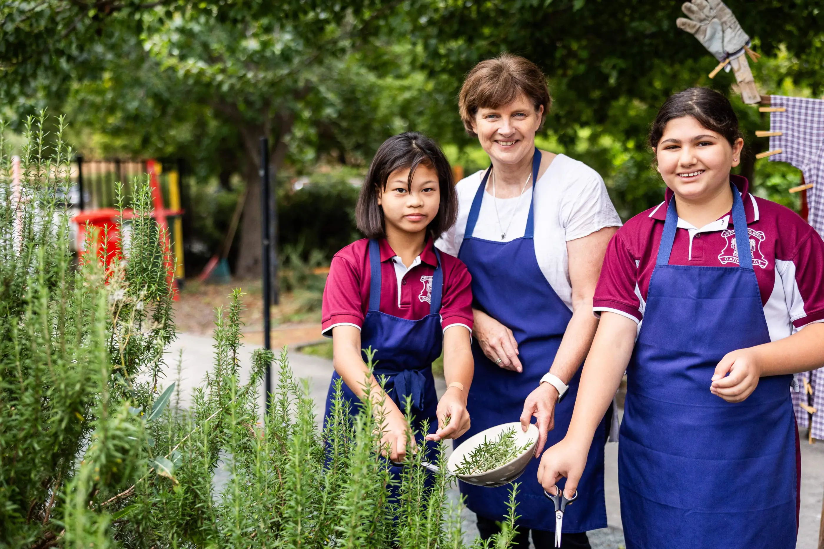 A teacher and two students gardening outdoors