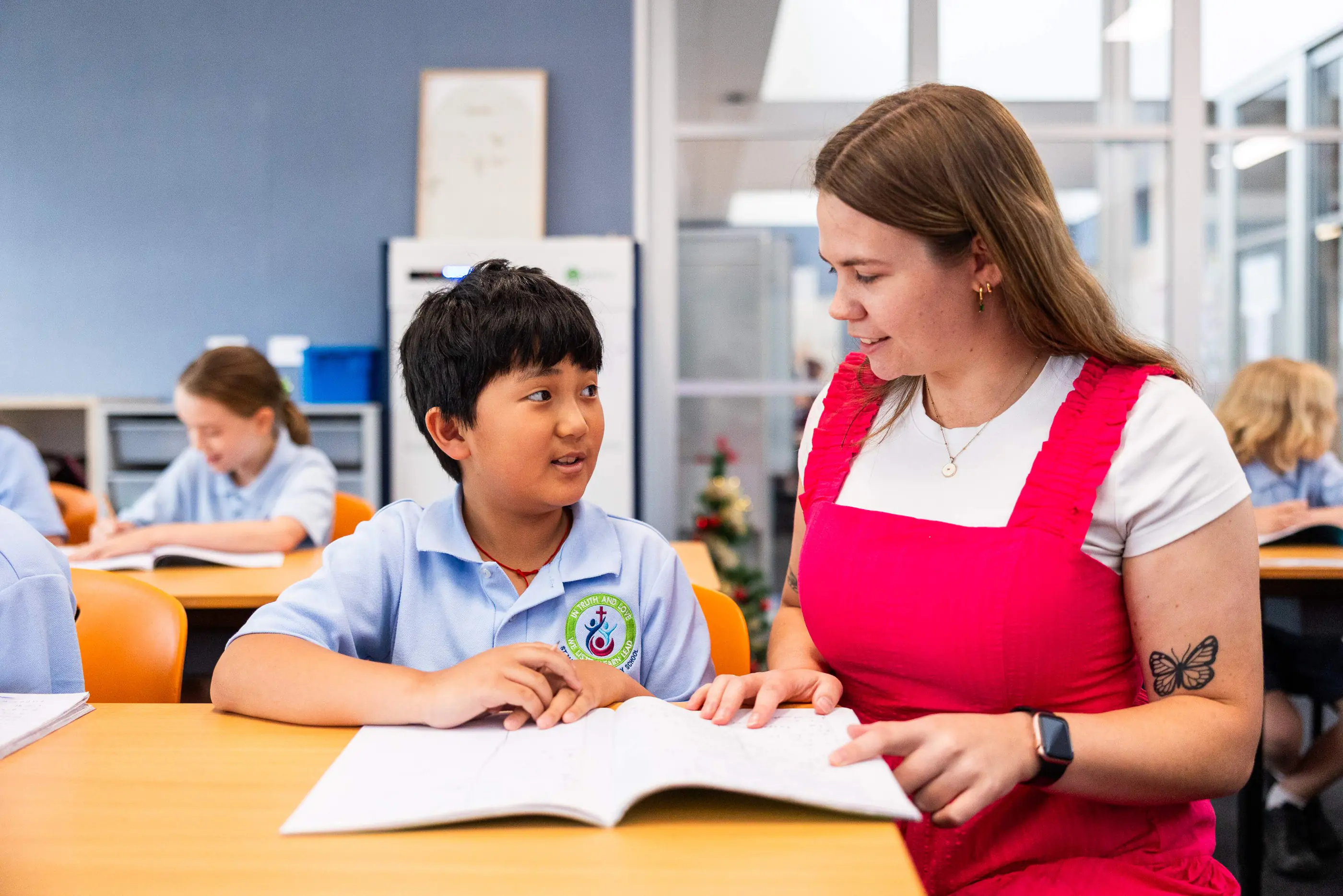 A teacher helping a primary school student in a classroom