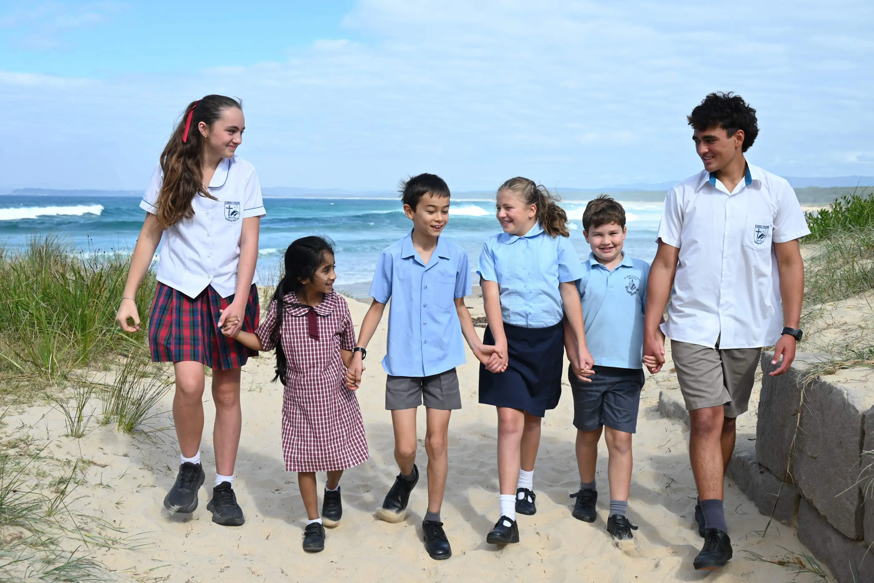 Students from different schools walking together on a beach