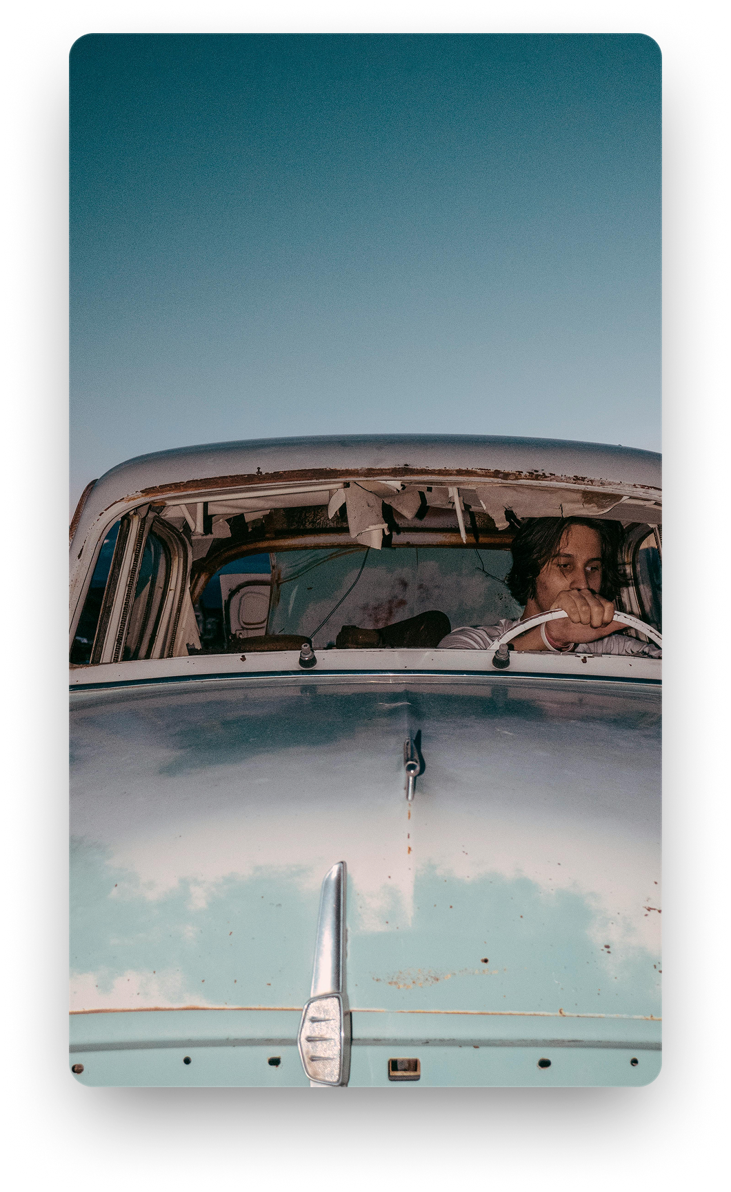 A person in the driver's seat of a car, looking ahead at the open road