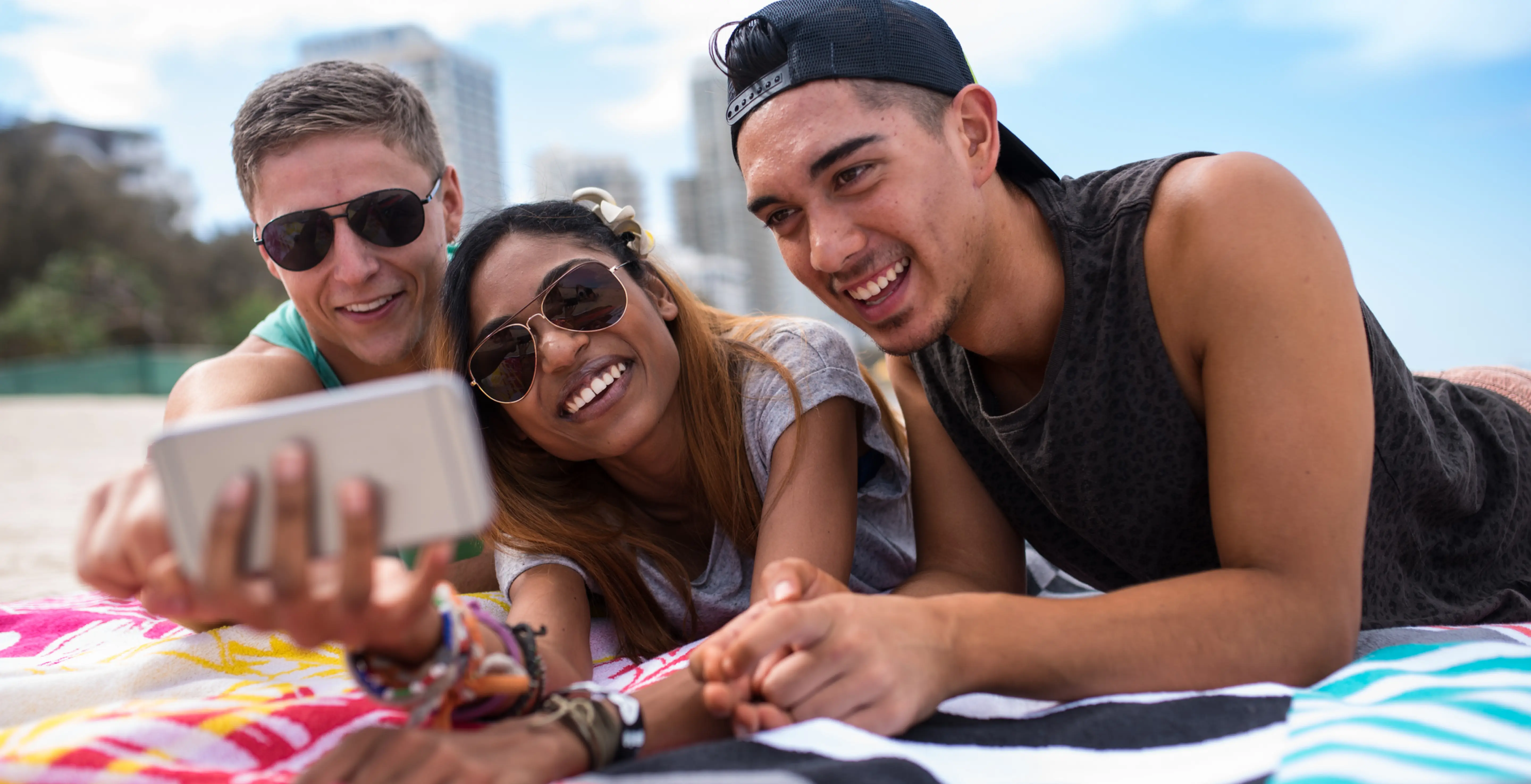 3 people on the beach looking at a mobile phone