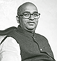 Black and white portrait of a man wearing glasses and a vest, facing the camera.