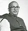 Black and white portrait of a man wearing glasses and a vest, facing the camera.