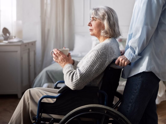 Smiling elderly couple embracing outdoors amid green leafy plants and trees.
