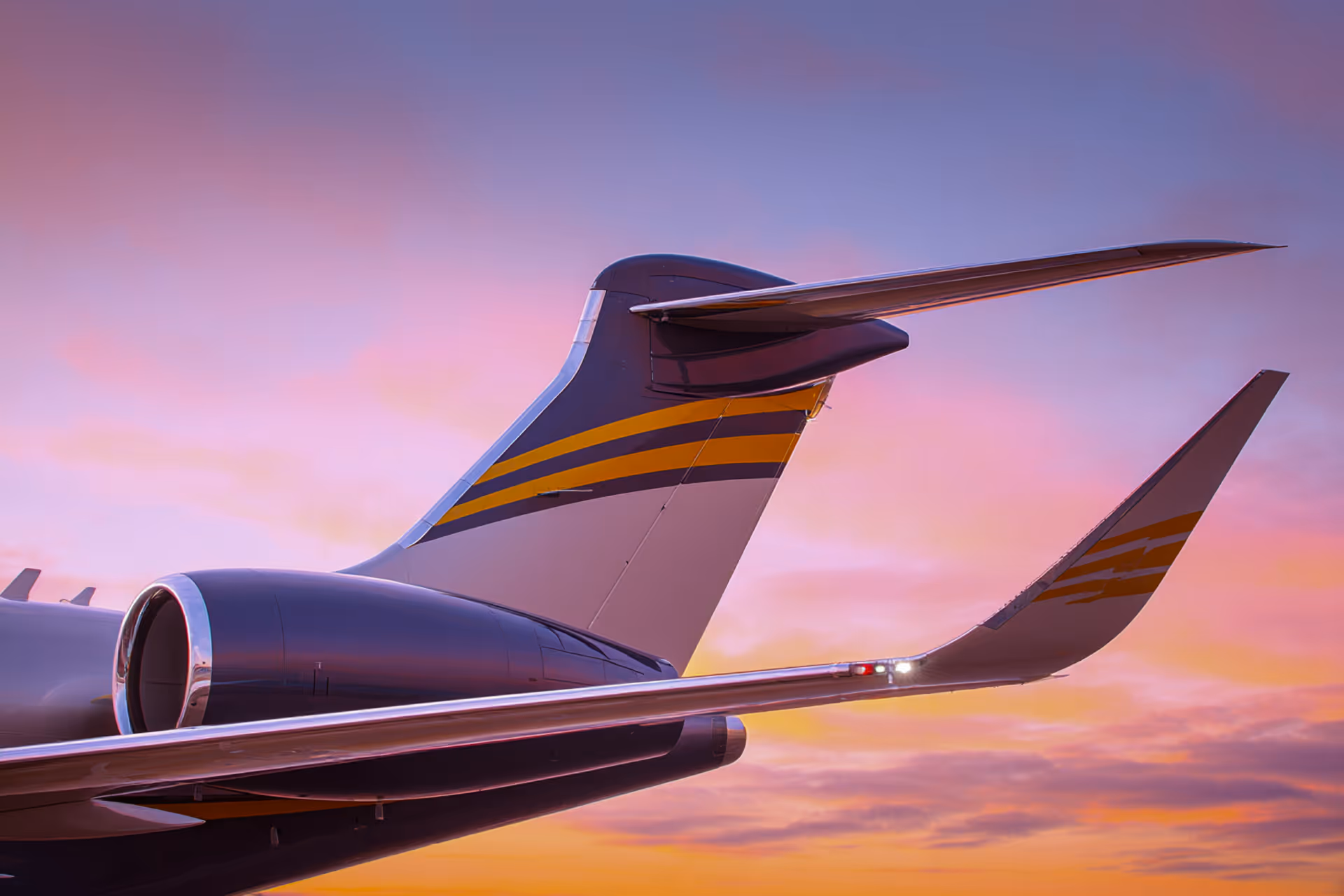 Close-up of an airplane's tail and engine against a colorful sunset sky.