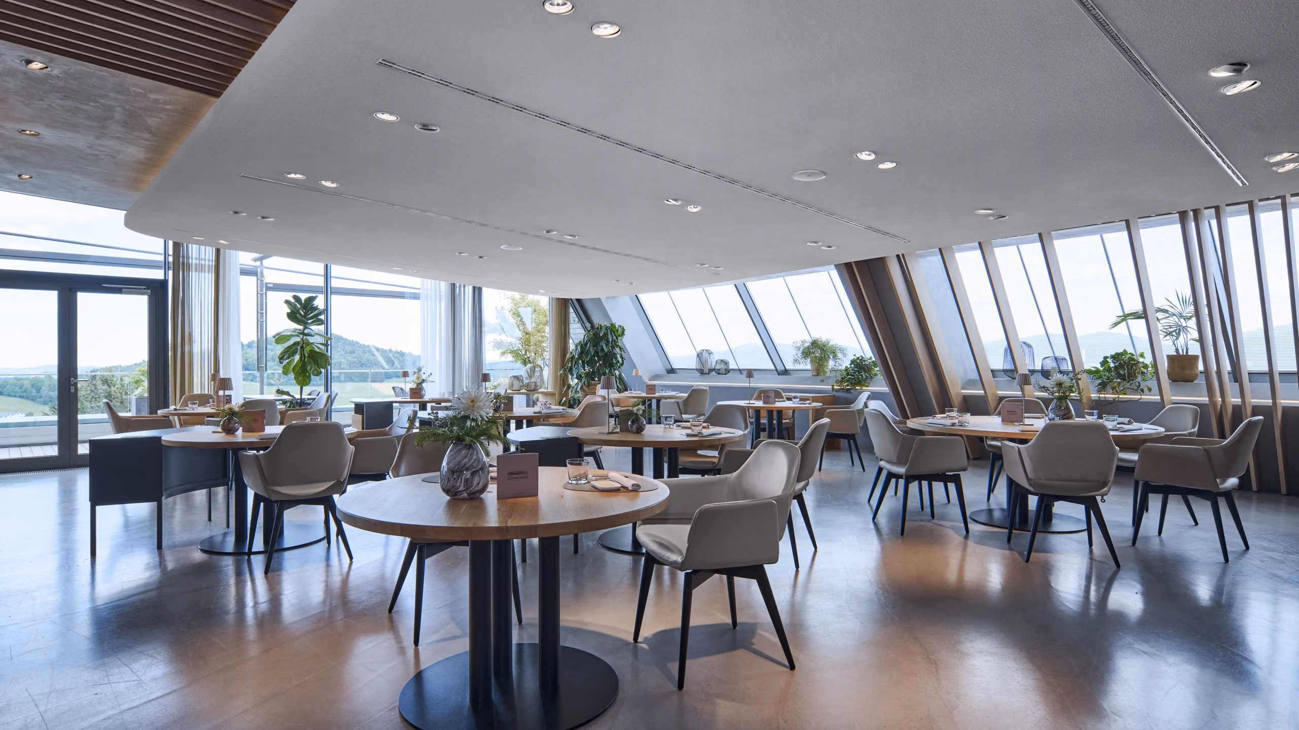 Speiseraum des Restaurant JOHANNS mit gedeckten Tischen und Blick durch die Fensterfront