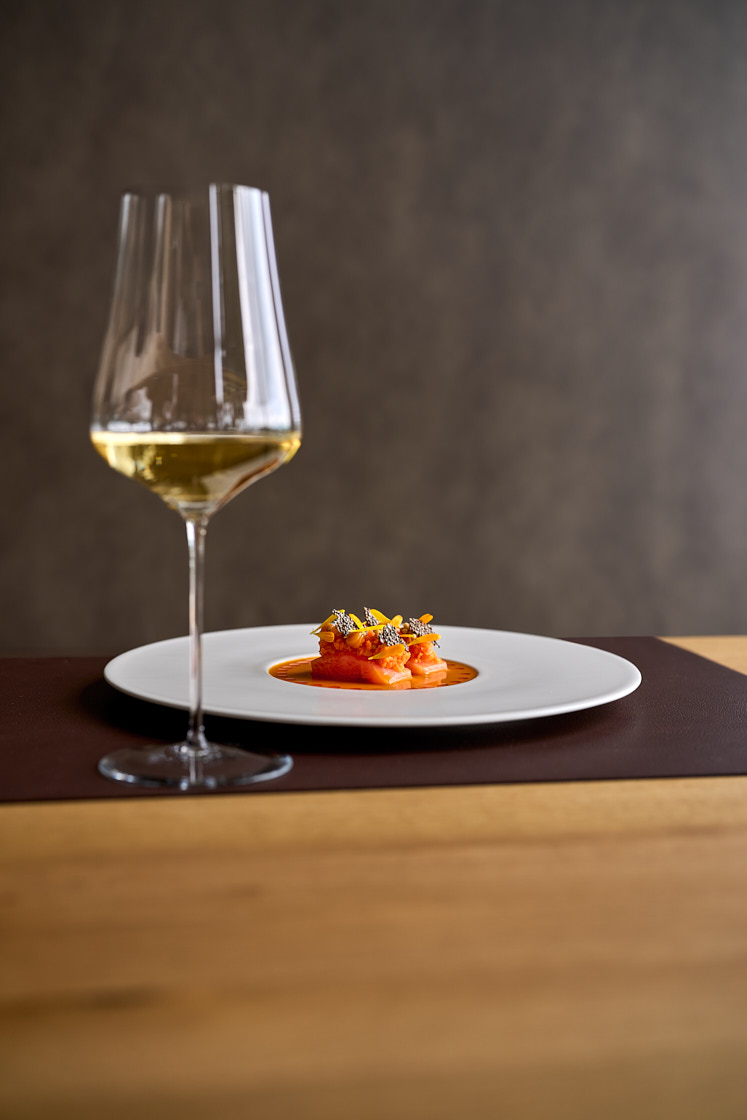 Glas Weißwein neben einem angerichteten Teller – Weinkarte im Restaurant JOHANNS