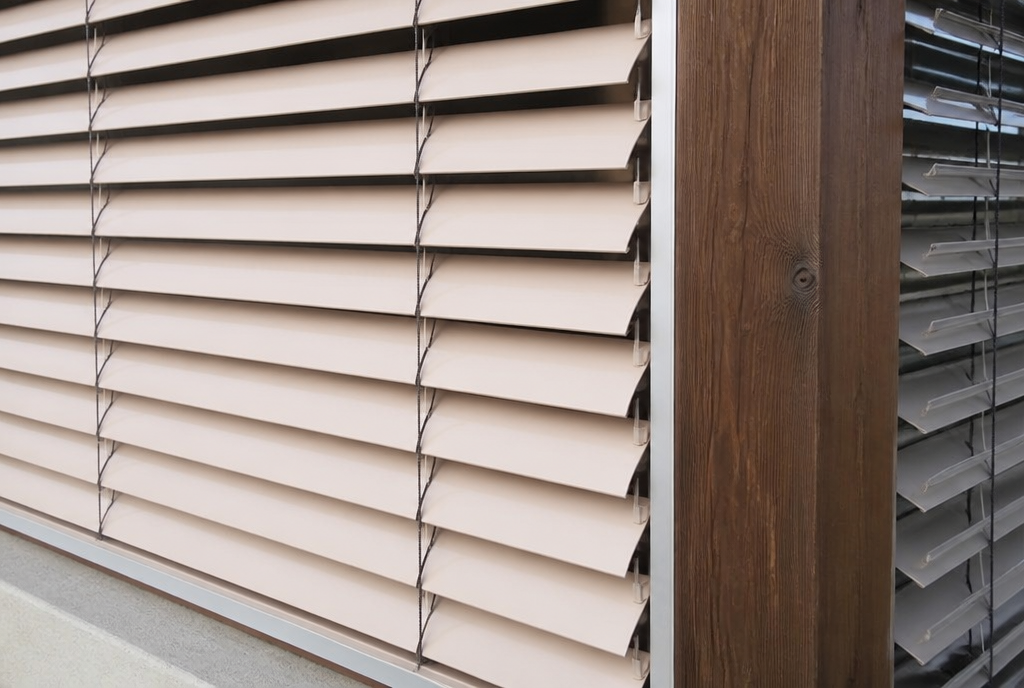 Detail des lames beiges du store exterieur et de sa coulisse contre le bois