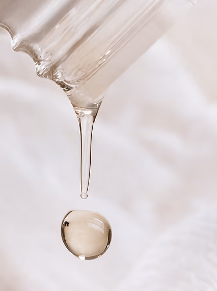 Druppel massageolie valt uit een glazen pipet