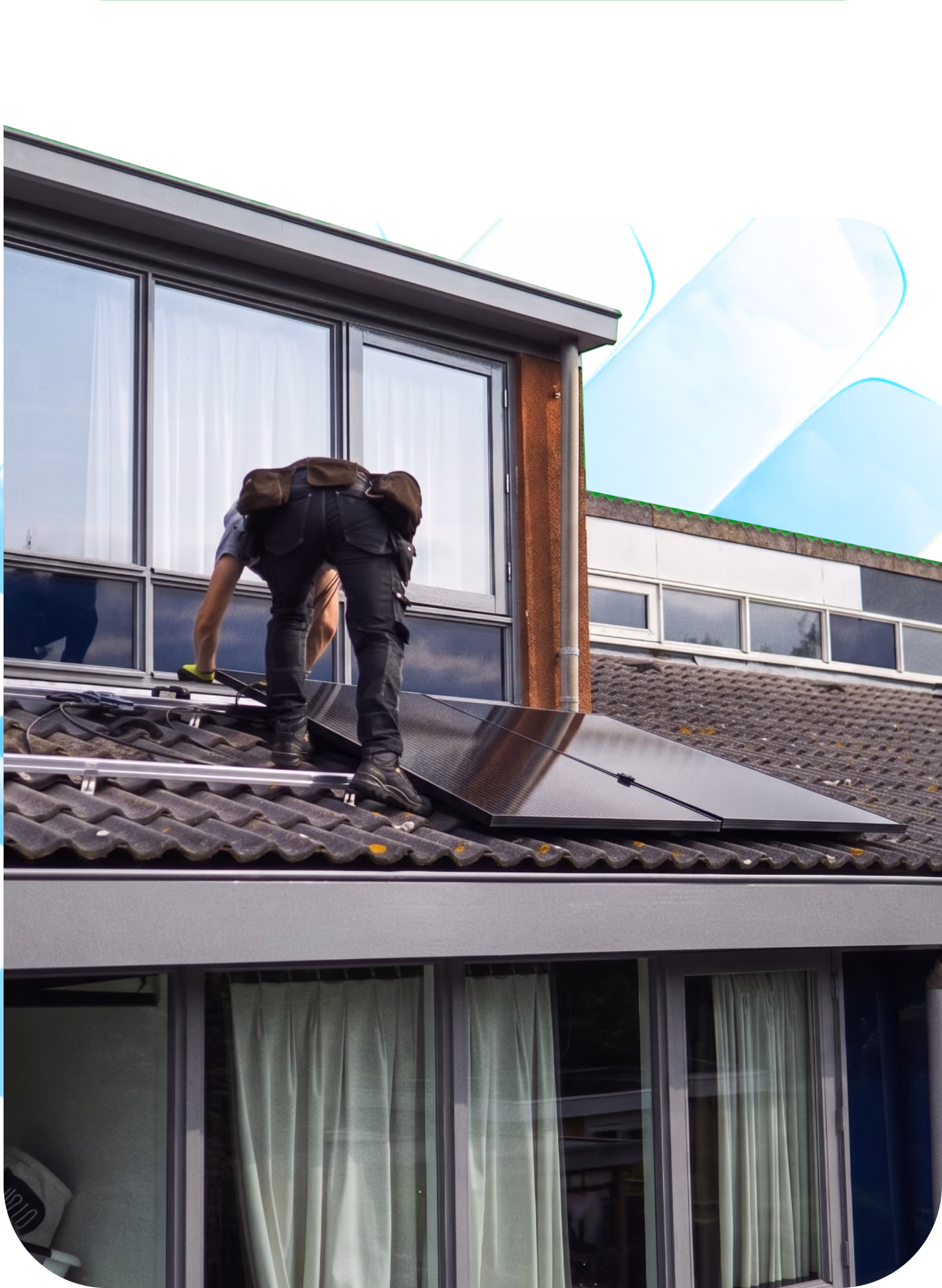 Installateur travaillant sur un toit avec des panneaux solaires, devant la fenêtre d'une maison