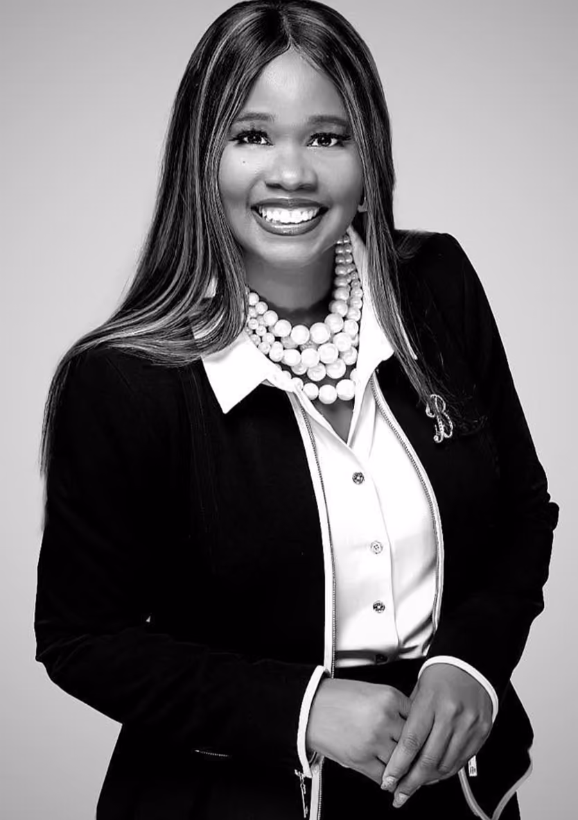 Black-and-white professional headshot of Pastor Bessie, a Chrysallis Lab client, smiling in a black blazer and pearl necklace