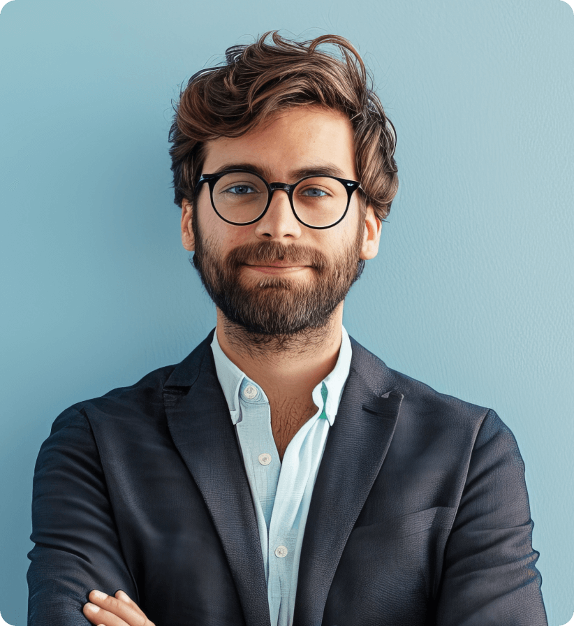 Smiling man with brown hair, beard, and black glasses wearing a dark blazer over a light blue shirt against a blue background.