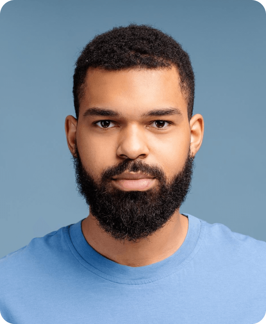 Portrait of a bearded man with short curly hair wearing a light blue shirt against a blue background.