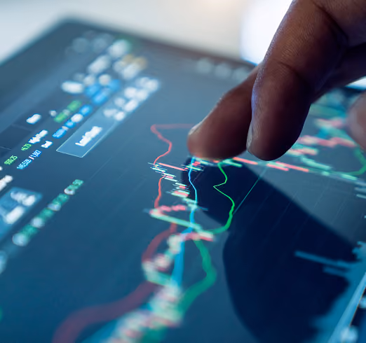Hand interacts with a touchscreen displaying colorful financial charts and stock market data.