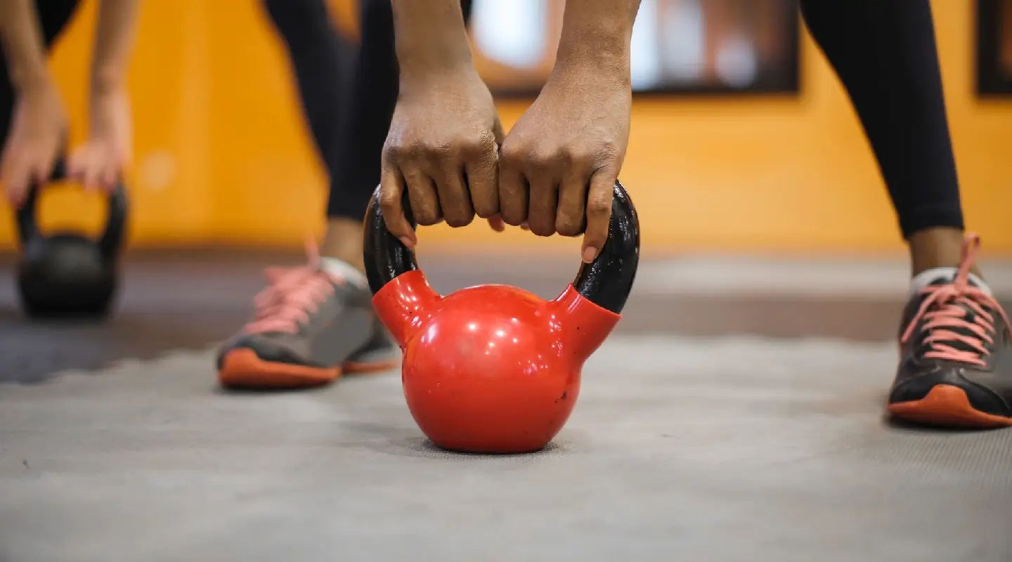 Close-up of an athlete gripping a red kettlebell during a strength training workout at House of Strength in San Diego, CA.