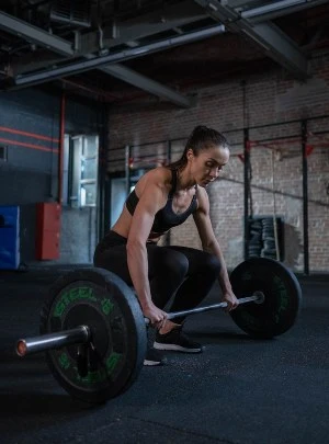 Athlete preparing to perform a barbell deadlift during a strength training workout at House of Strength in San Diego, CA.