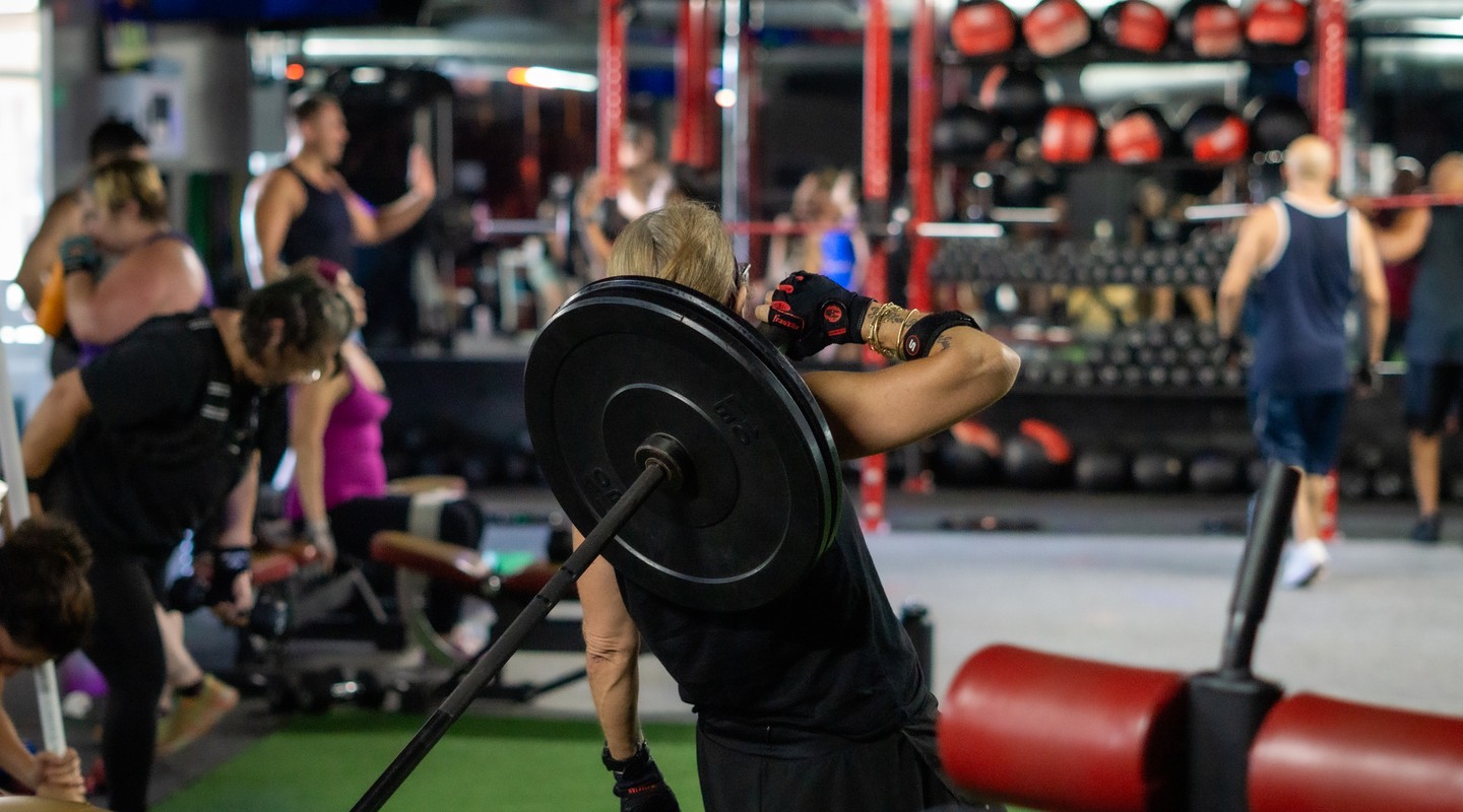 Athlete performing a barbell clean and press during a strength workout at House of Strength in San Diego, CA.