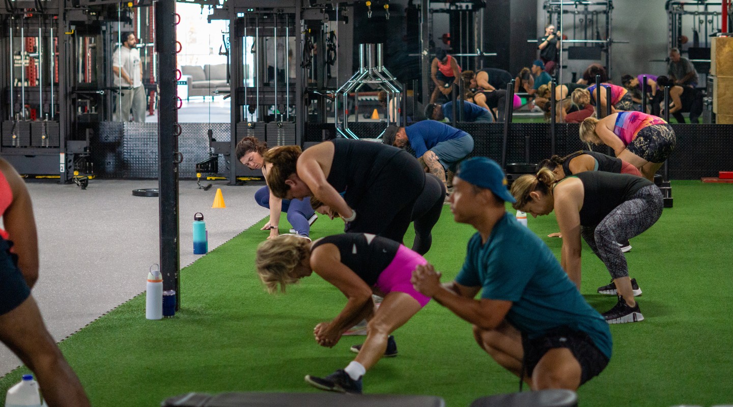 Group fitness class performing floor exercises together at House of Strength in San Diego, CA.