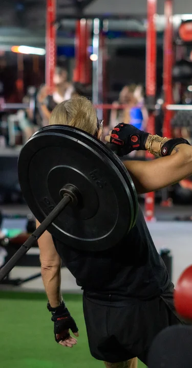 Athlete performing a barbell clean and press during a strength workout at House of Strength in San Diego, CA.