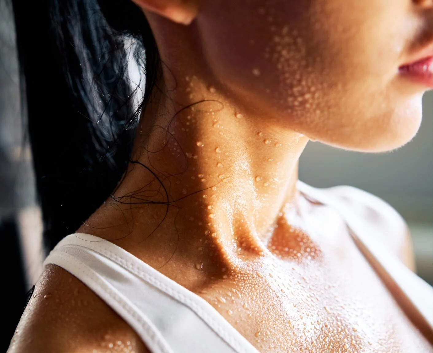 Close-up of a woman’s neckline with visible sweat droplets after exercise.