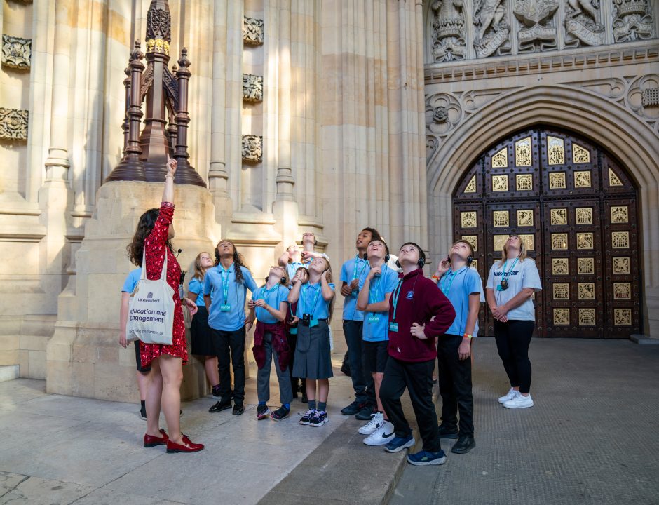 A group of pupils with their teacher standing outside Parliament
