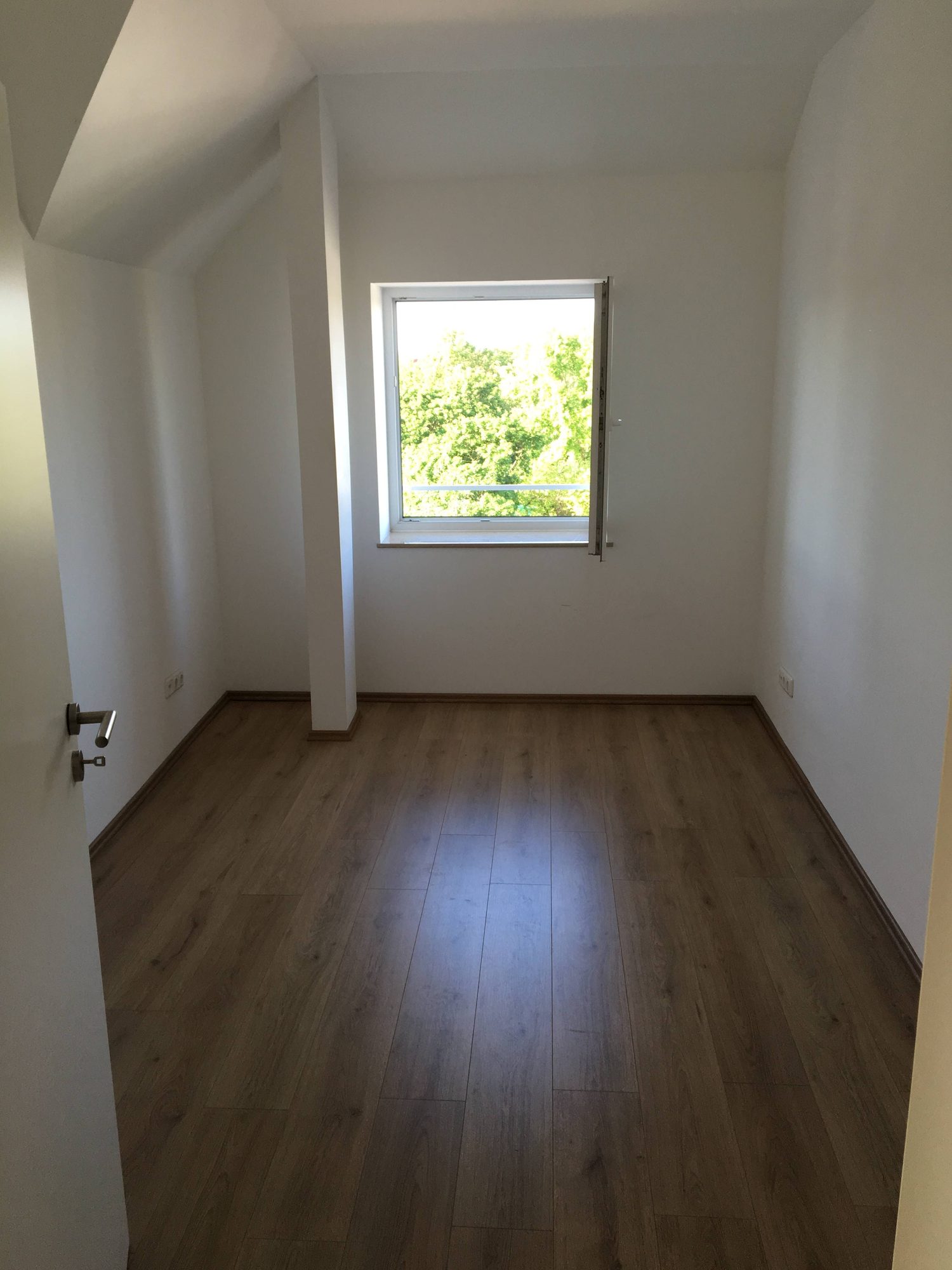Zimmer mit Fenster und Laminatboden