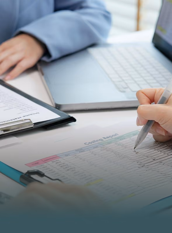 Person writing on a printed chart labeled 'Cooling Report' beside a laptop and clipboard on a desk.