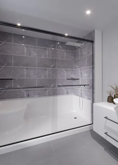 Modern bathroom with gray tiled shower enclosure and white vanity with round basin and decorative plants.