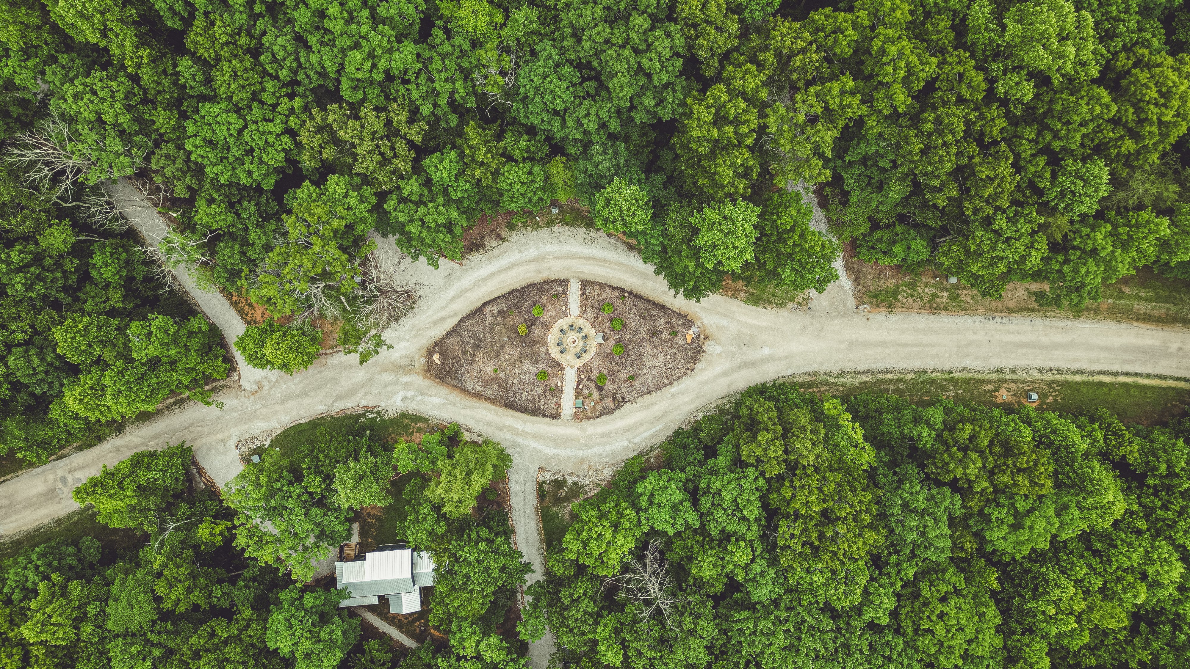 Aerial drone view of a circular garden driveway surrounded by green trees near the Sleepy Hollow cabin.