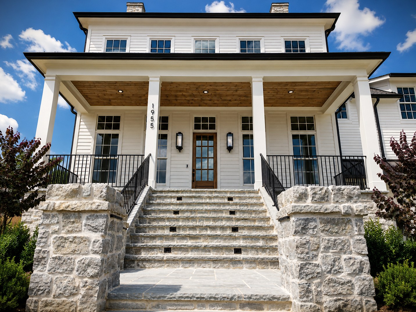 Two-story white colonial-style home built by Zurich Homes at 1955 Eliot Road, with a stone base and wide front steps.