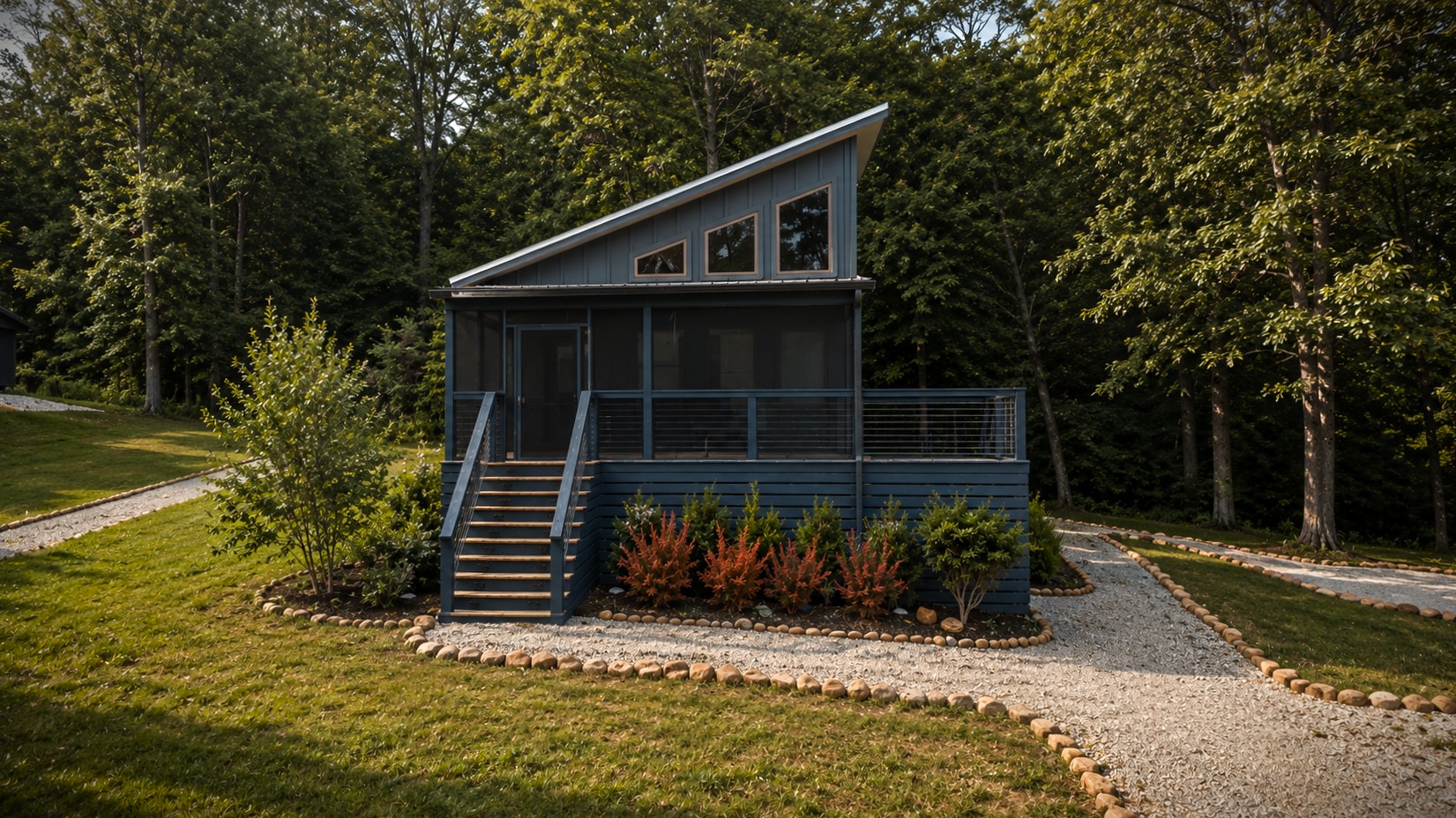 Blue modern cabin at the Retreat at Water's Edge with a covered porch and gravel landscaping.
