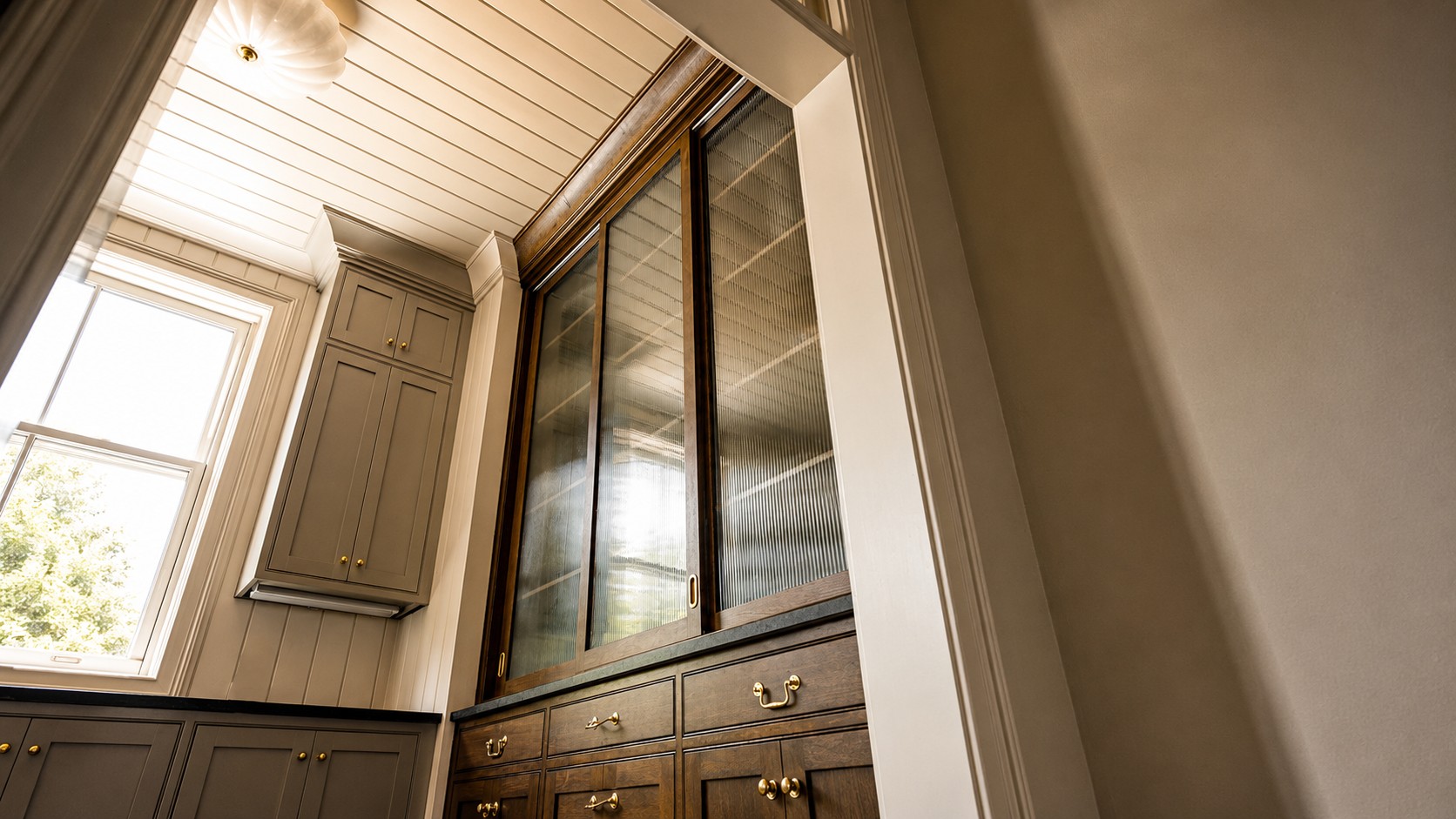 Butler's pantry at Magnolia Hall with glass-front cabinetry and brass hardware.