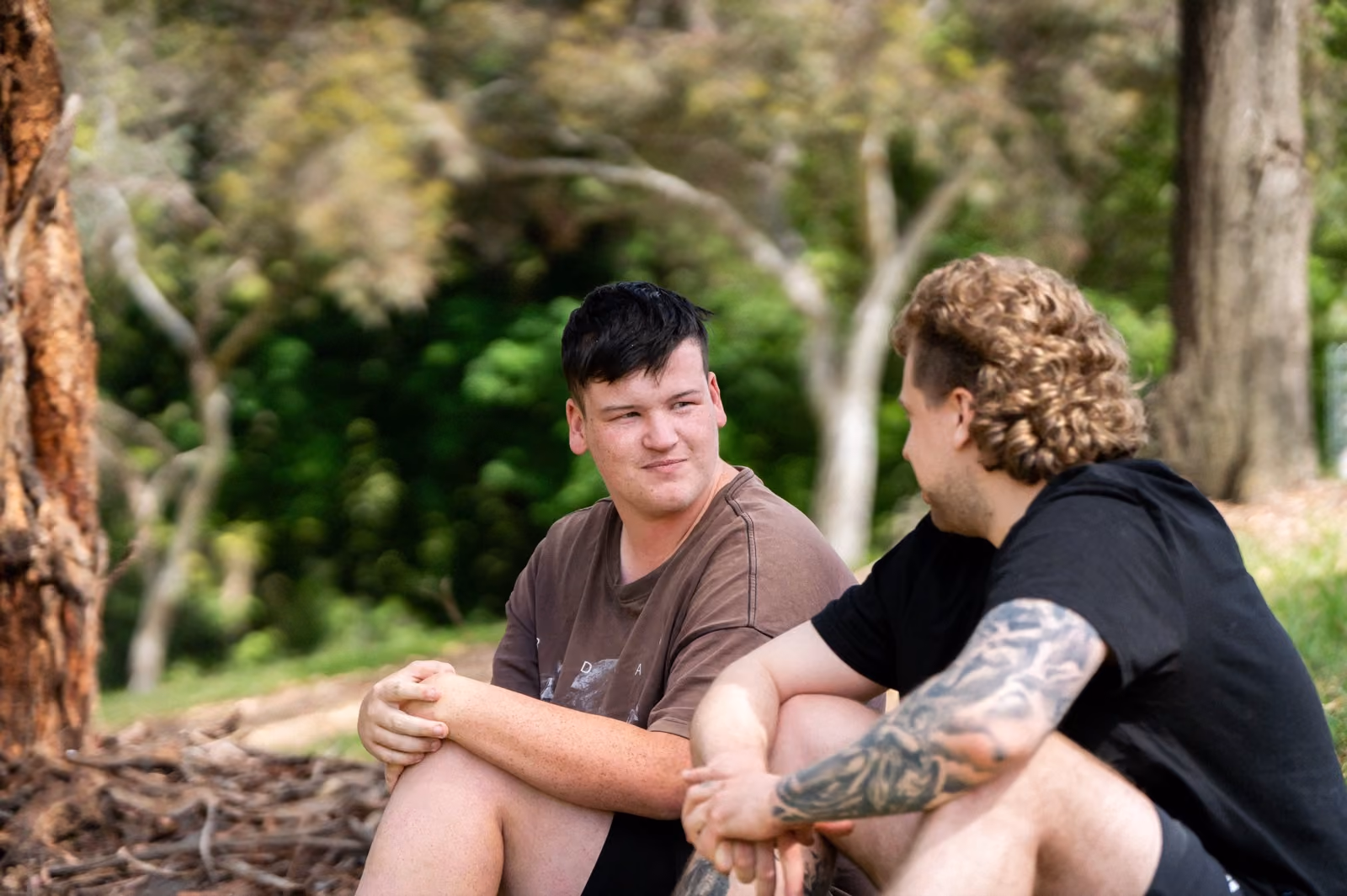 Two young men chatting together outdoors in the sunshine