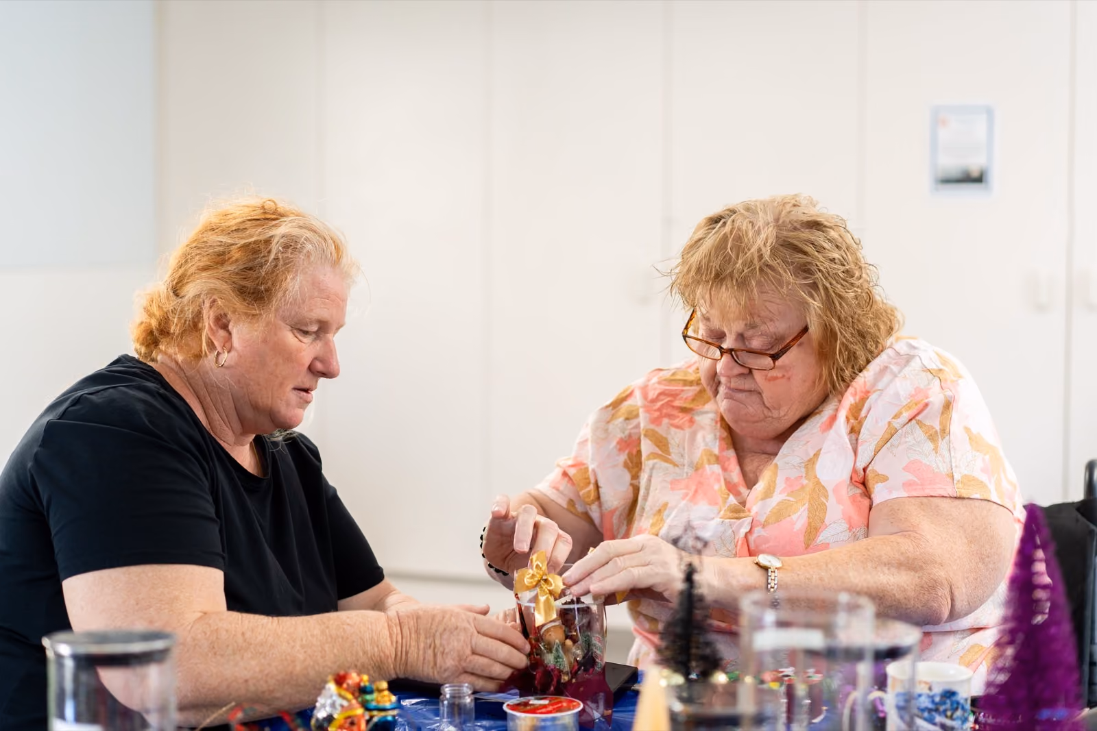 Two women working on a craft project together at a table at home