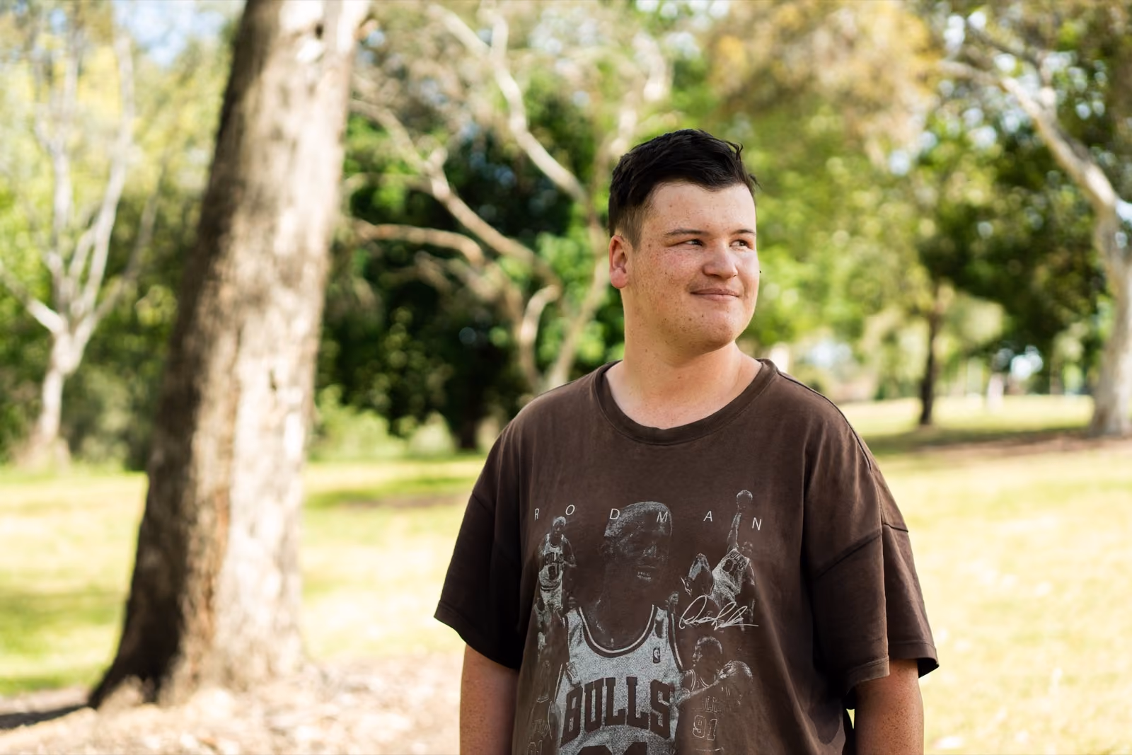 A young man standing in a park on a sunny day