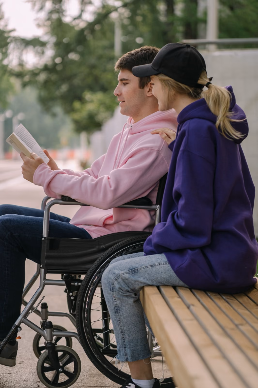 Two people sitting outside together, one reading a book