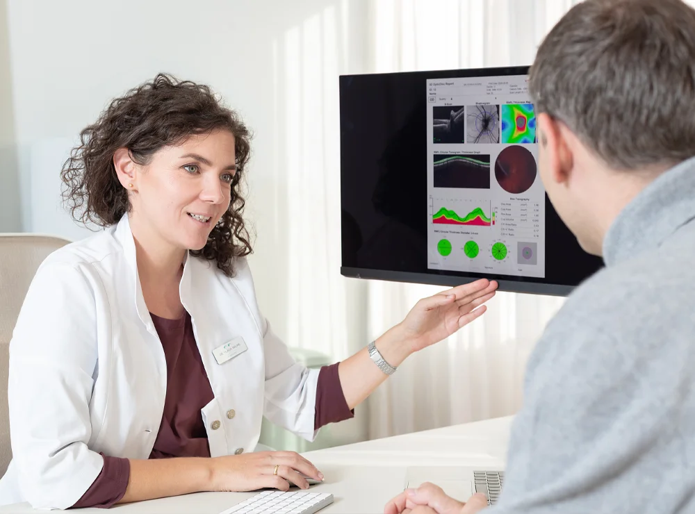 Augenärztin Dr. Vlada Wilms erläutert einem Patienten die Ergebnisse einer Augenuntersuchung am Bildschirm