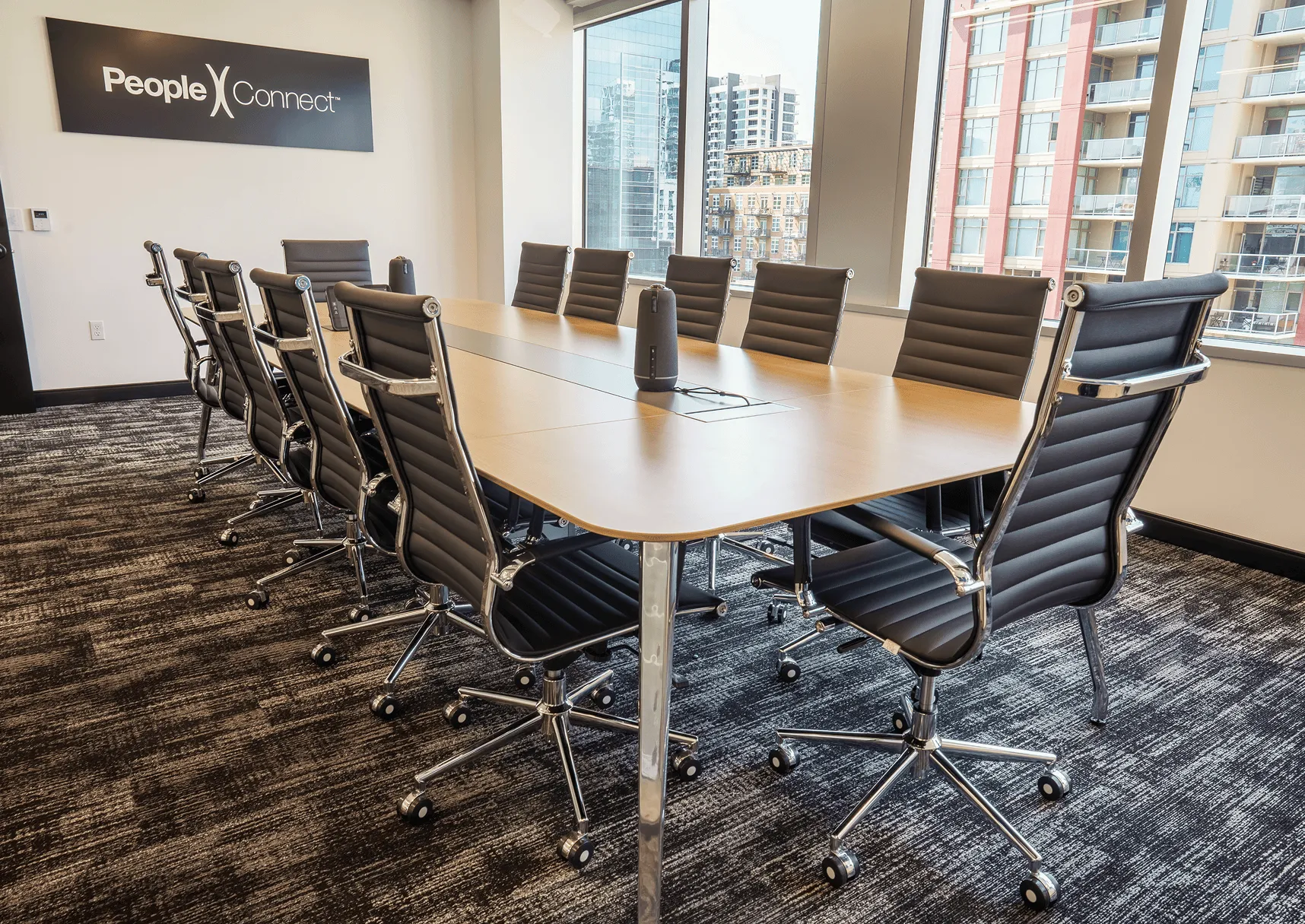 PeopleConnect's conference room with a long wood table, black leather chairs, and floor-to-ceiling windows framing the downtown San Diego skyline18:03