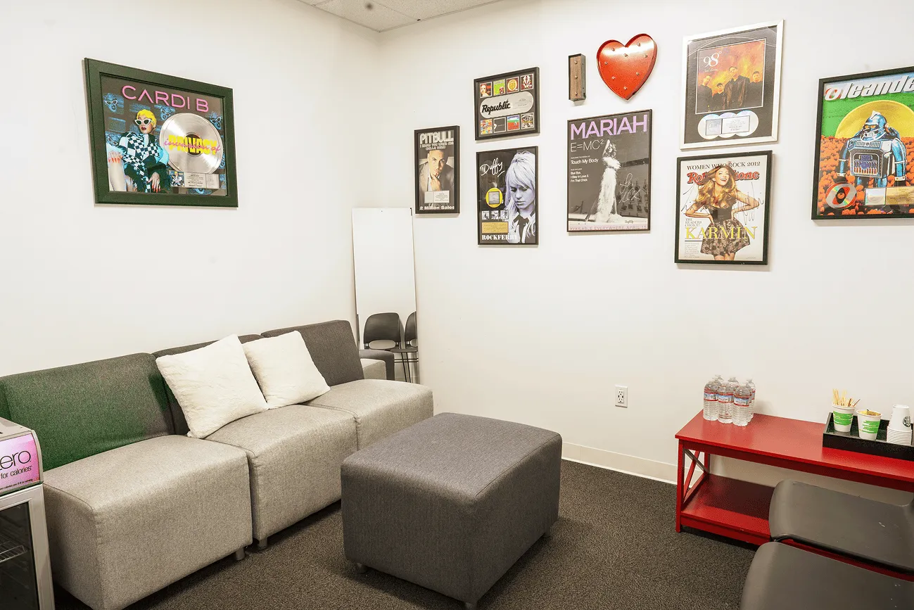 Artist green room at iHeartMedia San Diego decorated with framed gold and platinum records from artists including Cardi B, Pitbull, and Mariah Carey