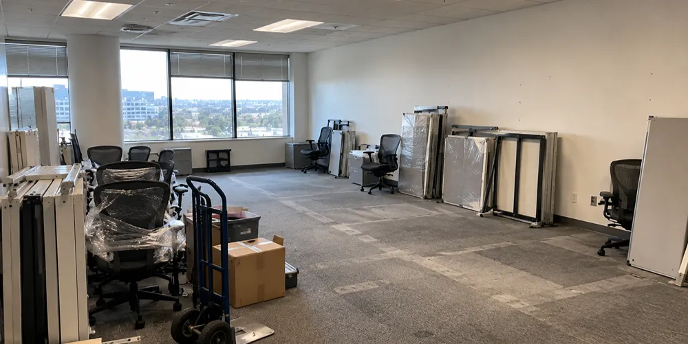 Empty office with chairs, workstation panels, and boxes staged for removal before a landlord walk-through