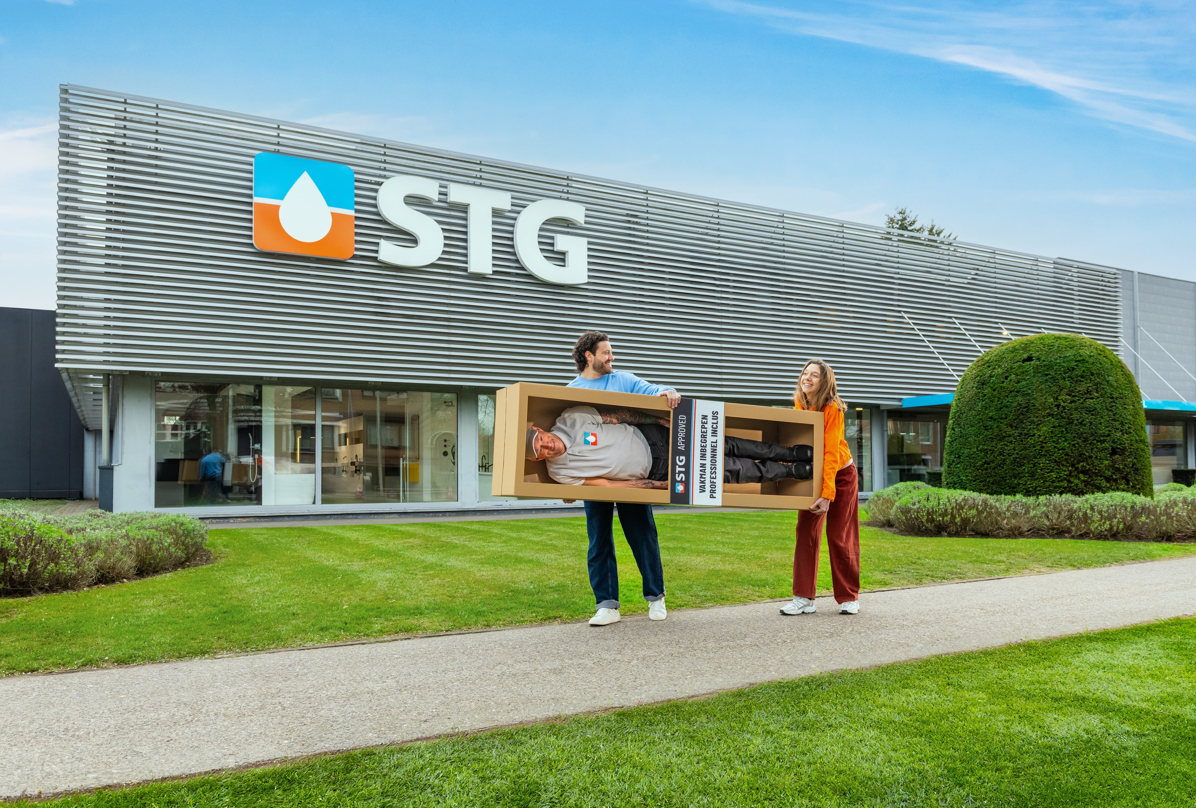 Koppel draagt een doos met een vakman erin buiten de STG-toonzaal