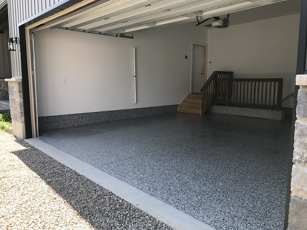 Two-car garage with a dark full broadcast flake epoxy floor and cove base