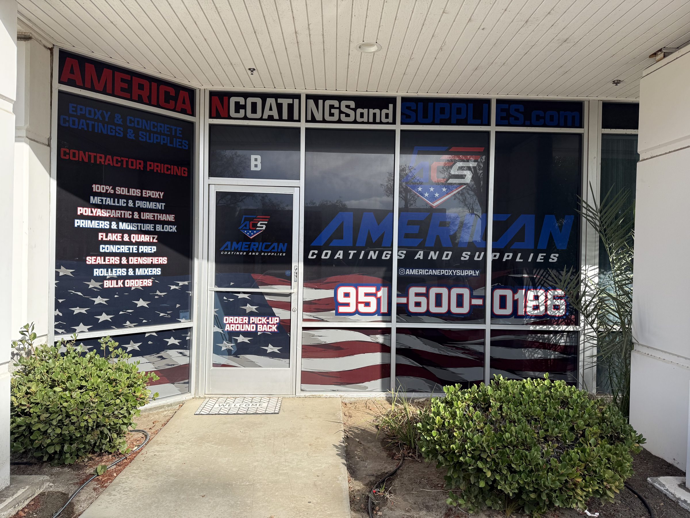 Front of the American Coatings and Supplies store in Murrieta, with American flag window wraps, product list on the glass, and the Suite B door