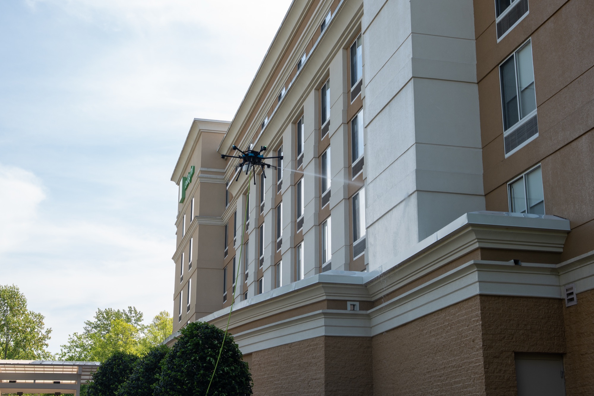 Cleaning drone spraying the upper facade of a multifamily building