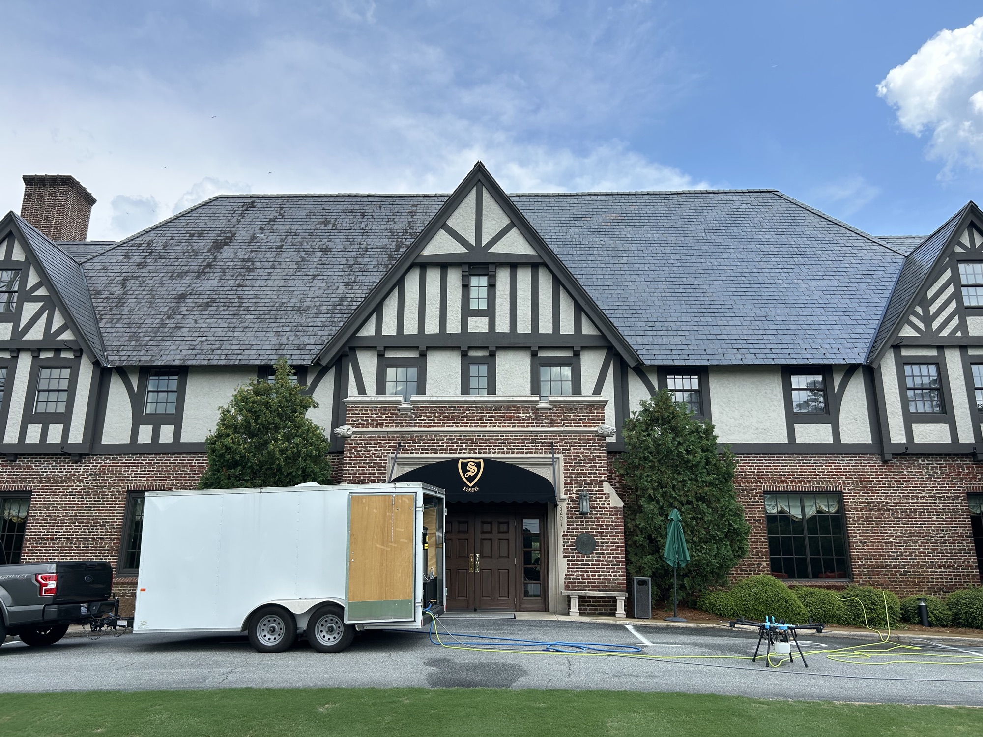 Sedgefield Country Club Tudor clubhouse roof, one side stained and one side cleaned, before-and-after of a drone soft wash