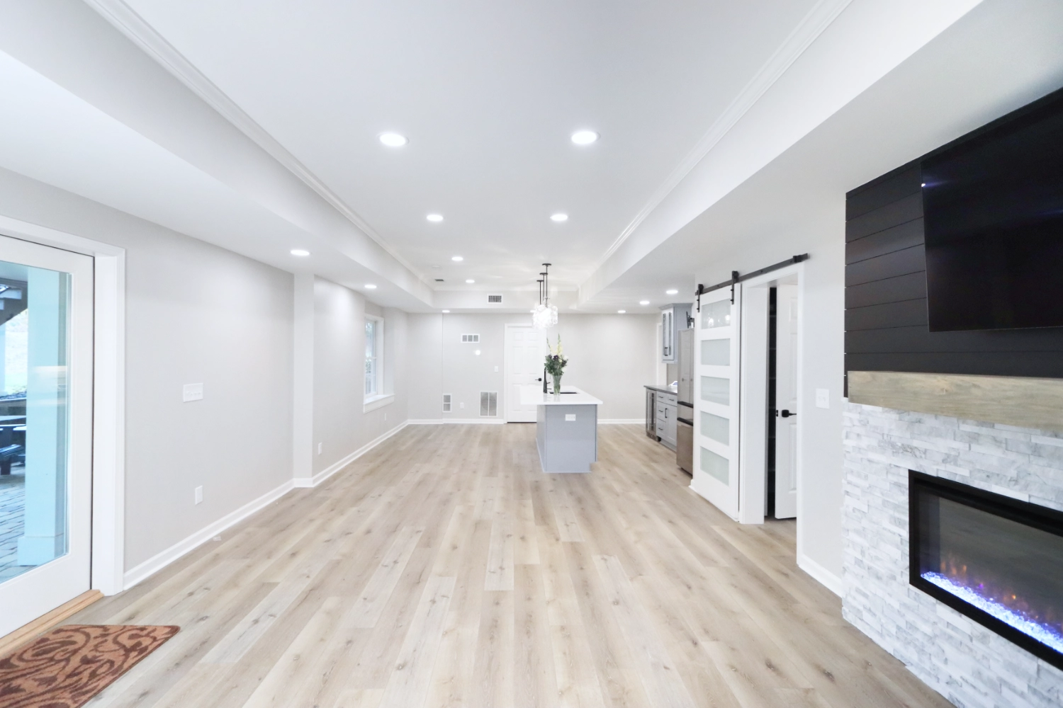 Sitting room with fireplace and wall mounted television looking into kitchenette