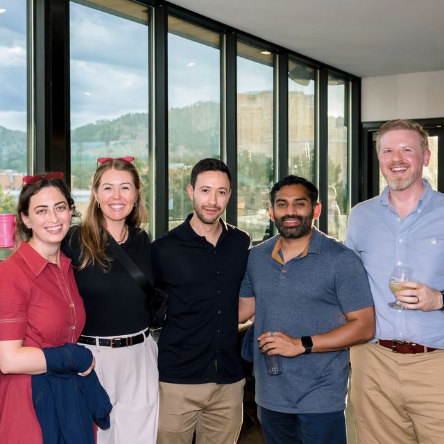 Five teammates gathered by the office windows with a mountain view