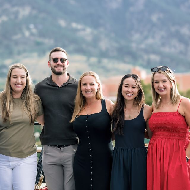 Five teammates on the rooftop deck at golden hour