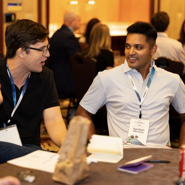 Two teammates talking across the table at a conference dinner