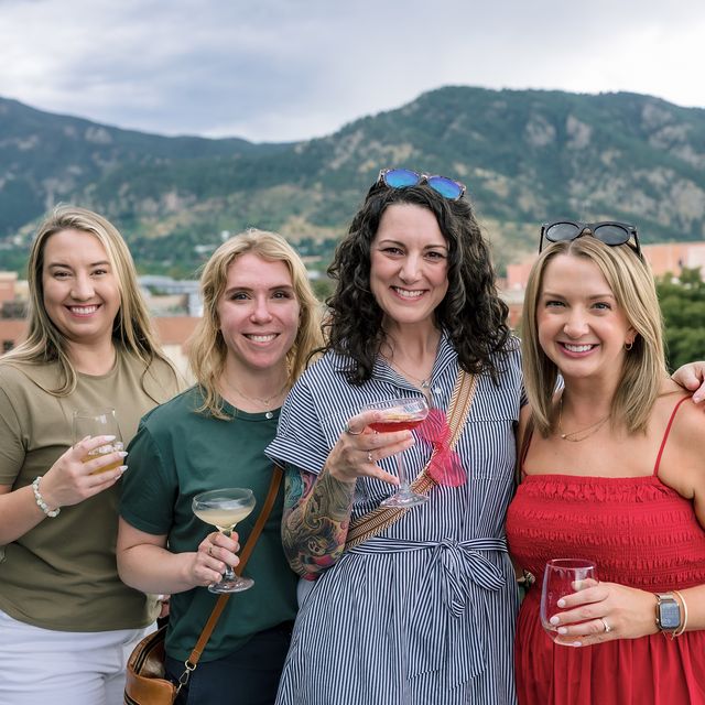 Four teammates with drinks on the rooftop deck